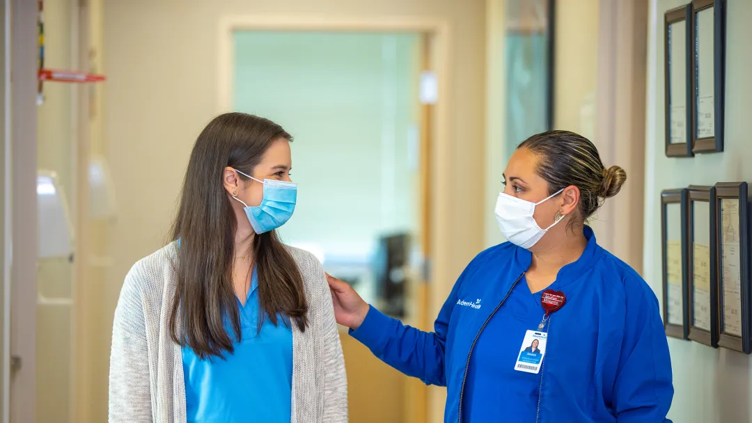 Nurse with her hand on patient in hallway at outpatient clinic
