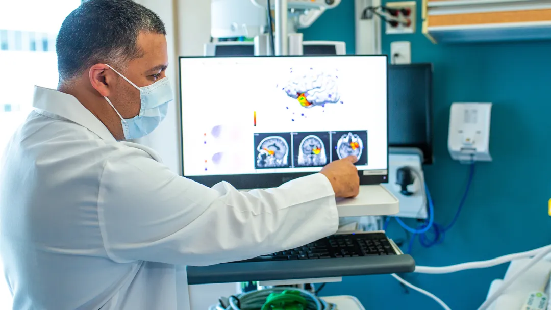Physician pointing at a brain scan on a screen.