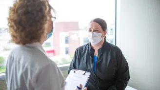 Patient speaking to her doctor, both wearing masks