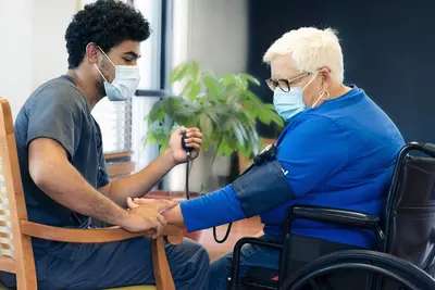 A health care professional checks a woman's blood pressure.