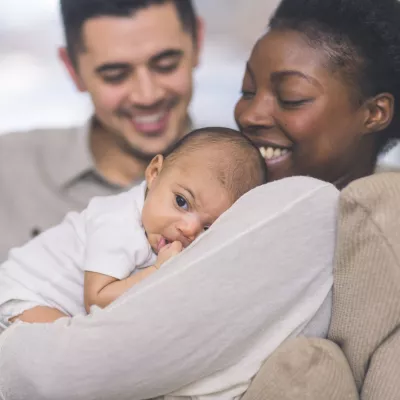 A New Mom Holds Her Baby While While Her Husband Smiles