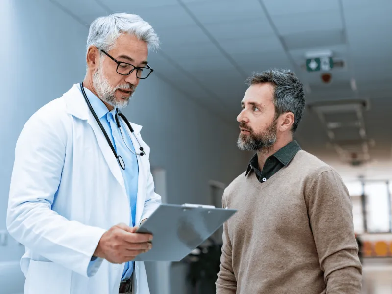 A Doctor Speaks to a Patient in the Hallway of a Practice.