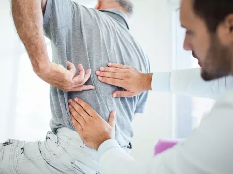 A Senior Patient Points Out to His Doctor where on His Back the Pain is