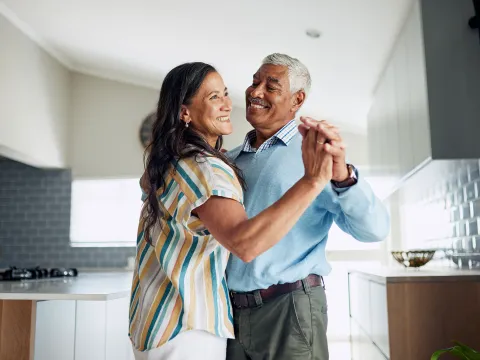 senior couple joyfully dancing together in kitchen