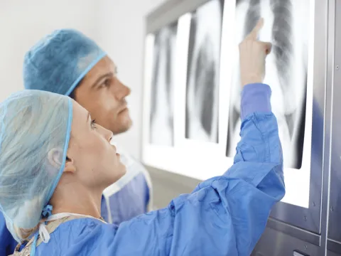 two doctors in scrubs examining a lung x-ray