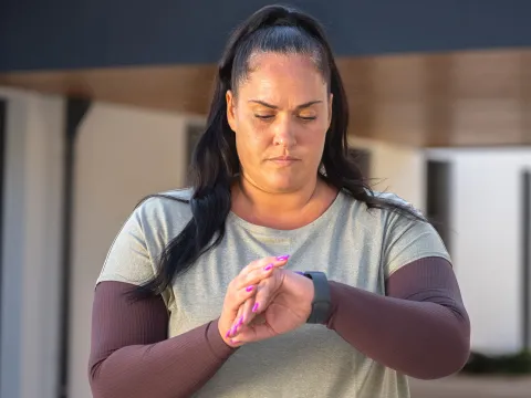 A woman checks her watch during exercise. 
