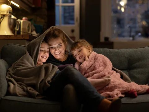 Mother and kids watching videos underneath covers