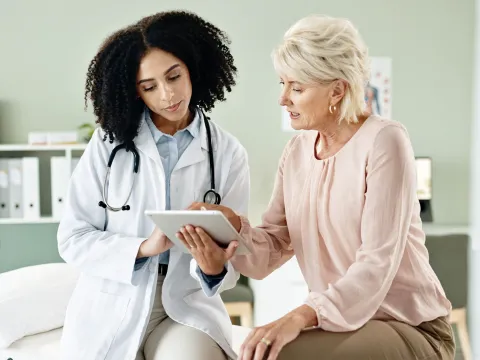 A woman looking at medical info on a tablet with her doctor.