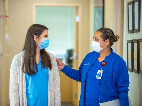 Nurse with her hand on patient in hallway at outpatient clinic