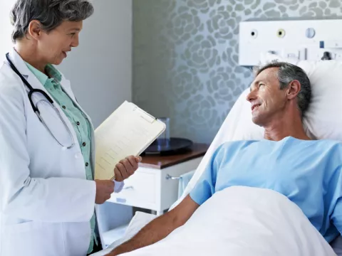 Doctor speaks to a patient who is lying in a hospital bed