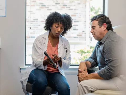 A female doctor showing a male patient test results in a examination room.