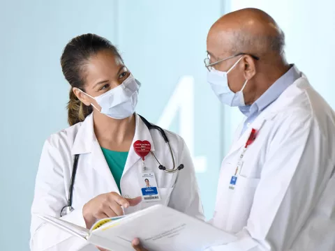 Two doctors talking while wearing masks.