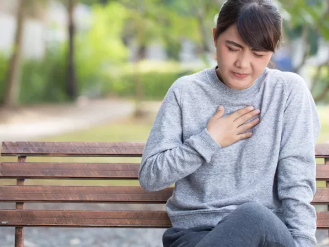 Woman experiencing heart burn in a park