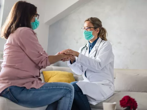 A female physician holding a female patient's hand