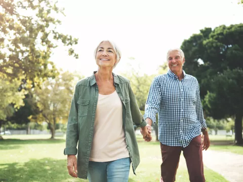 Elderly couple holding hands and walking in a park