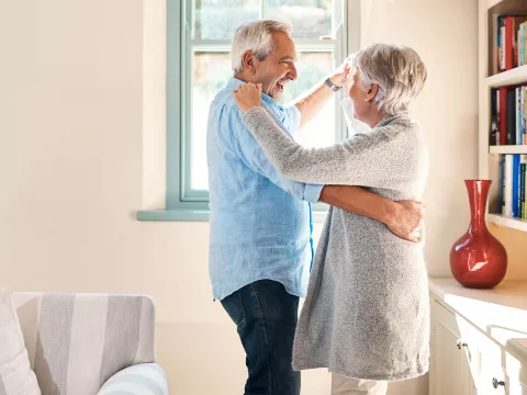 A mature couple dancing at home.