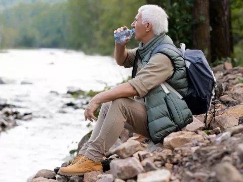 A man taking a water break on a hike.