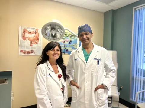 Tina Ellison smiling on the left of Dr. Abubaker Ali smiling on the right.