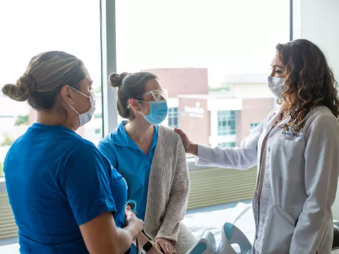 Physician and nurse talking with a patient.