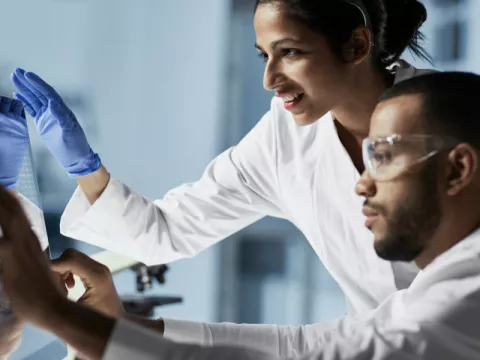 Two lab technicians reviewing results on a computer screen