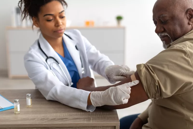 A Physician Puts a Bandage on an Injection Site After a Vaccine