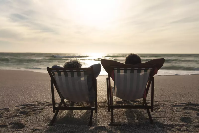 Older couple lounging in beach chairs while on the beach.