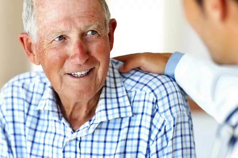 Doctor with his hand on an elderly man's shoulder