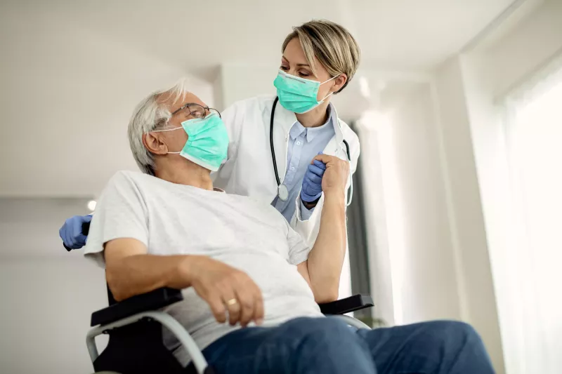 A doctor helping her senior patient on a wheelchair