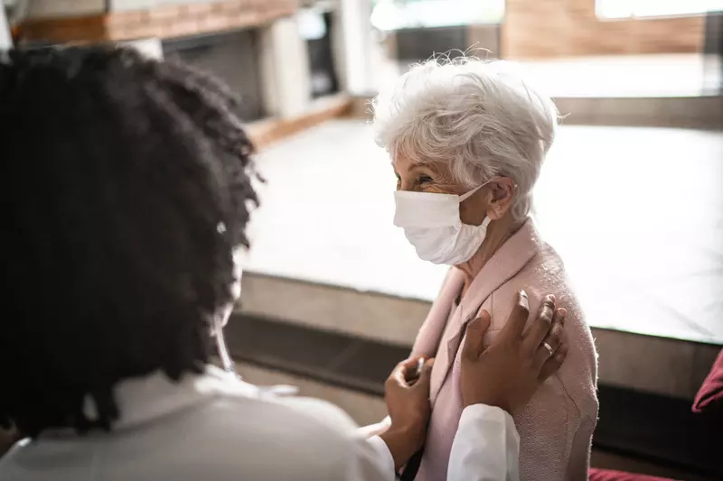 An elderly woman being comforted by her doctor