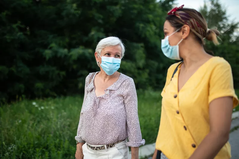 Two ladies talking while wearing masks