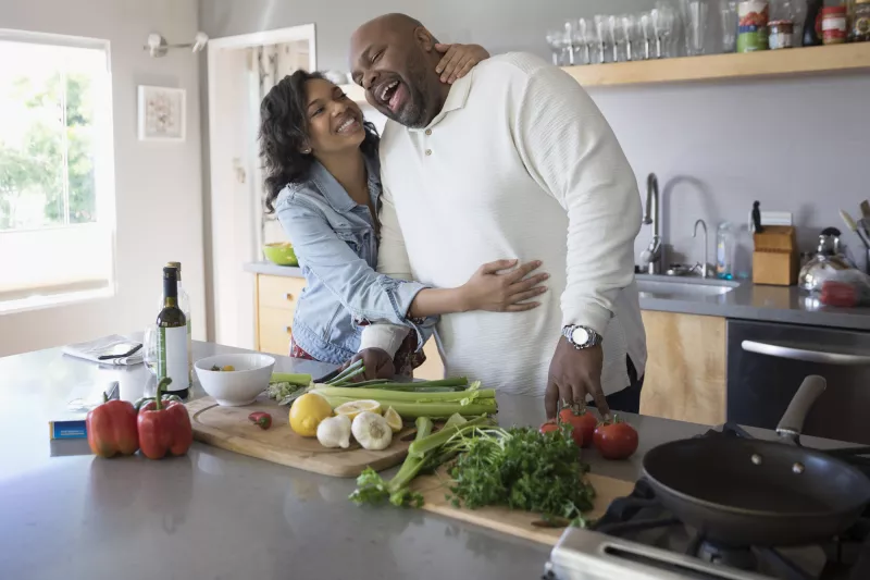A father and daughter having fun while cooking a healthy meal together.