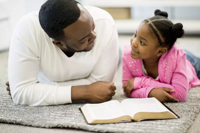 A father and daughter read the Bible together.