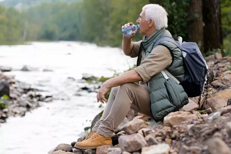 A man taking a water break on a hike.