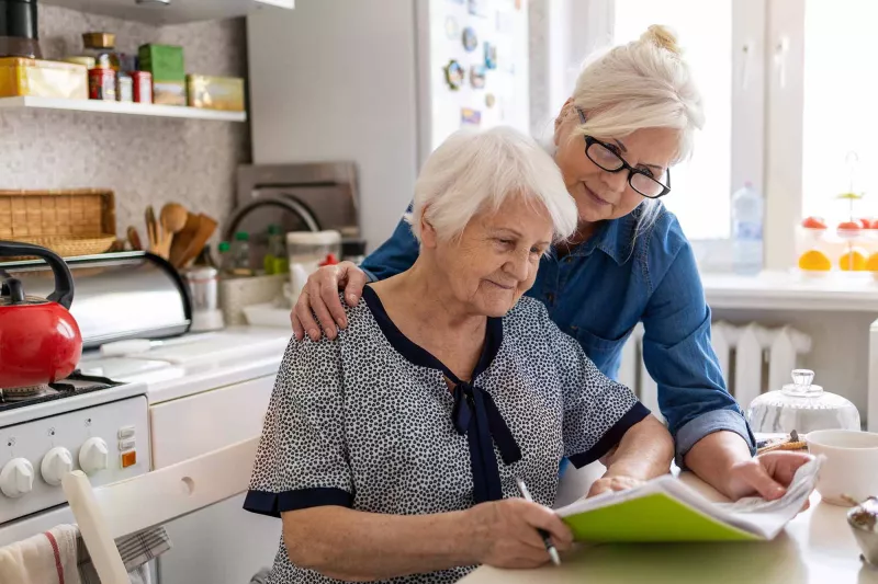 Woman with arm around mother looking at paperwork