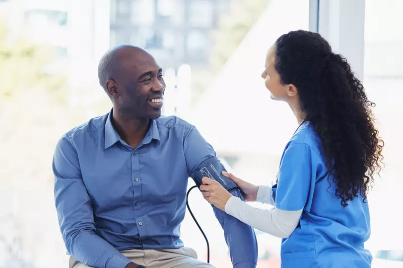 A male patient getting his blood pressure checked by a nurse.