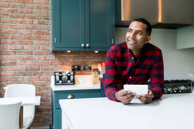 Smiling Man in Home Kitchen with a Tablet