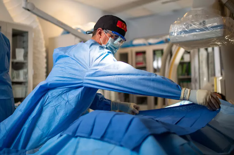 Neurosurgeon placing surgical drape over patient.
