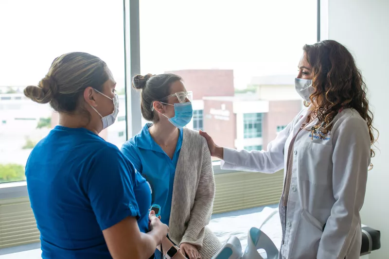 Physician and nurse talking with a patient.