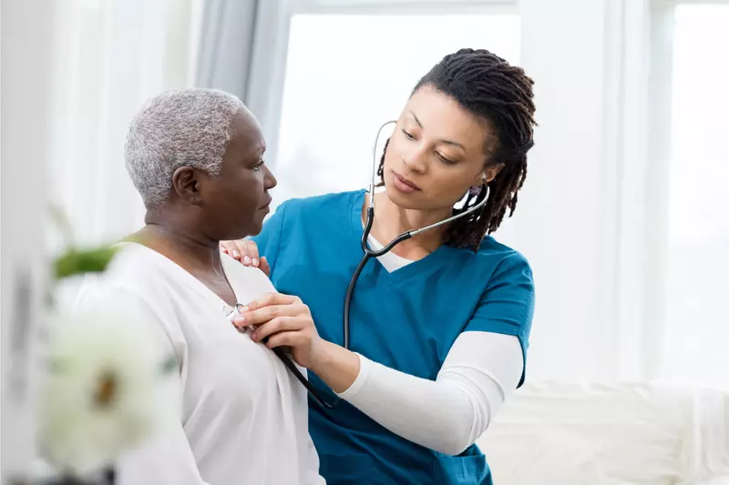 Nurse checking a woman patient's heartbeat.