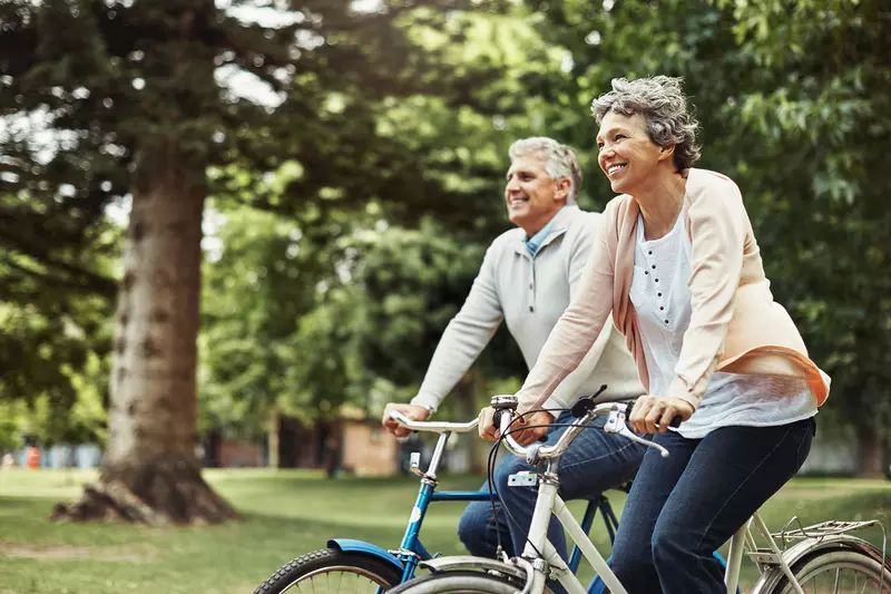 Older couple riding bicycles outdoors.