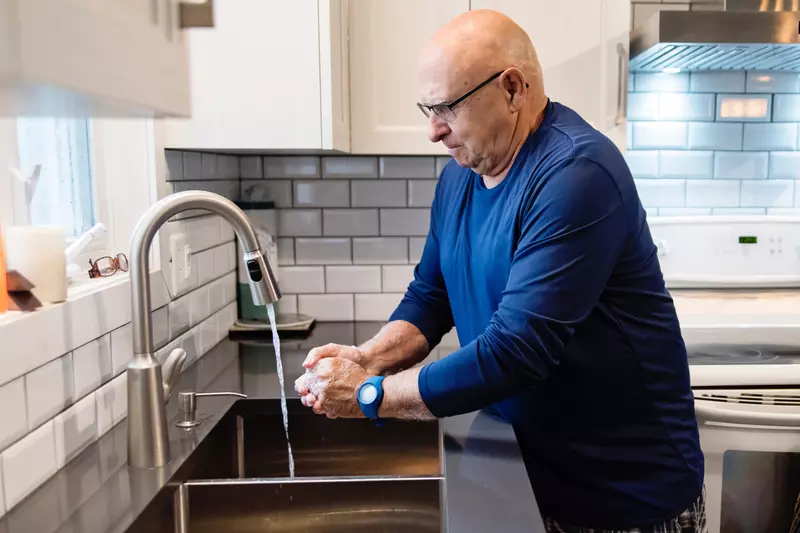 Senior man washing his hands at his home's kitchen sink
