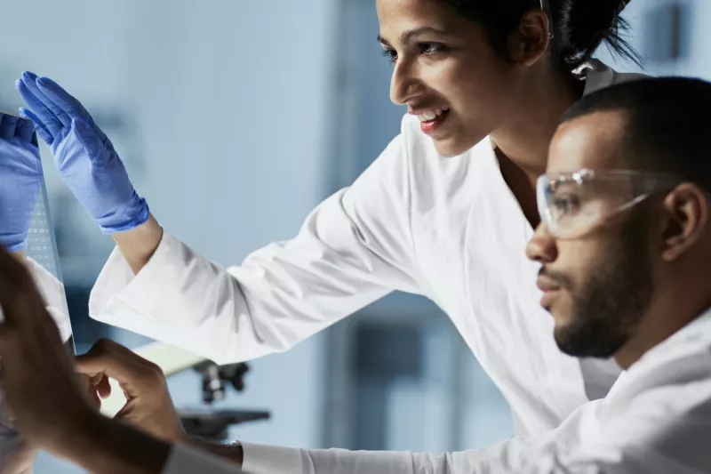 Two lab technicians reviewing results on a computer screen