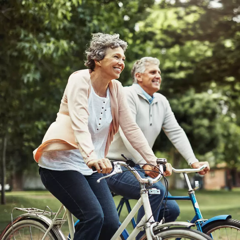 Older couple riding bikes outdoors together,