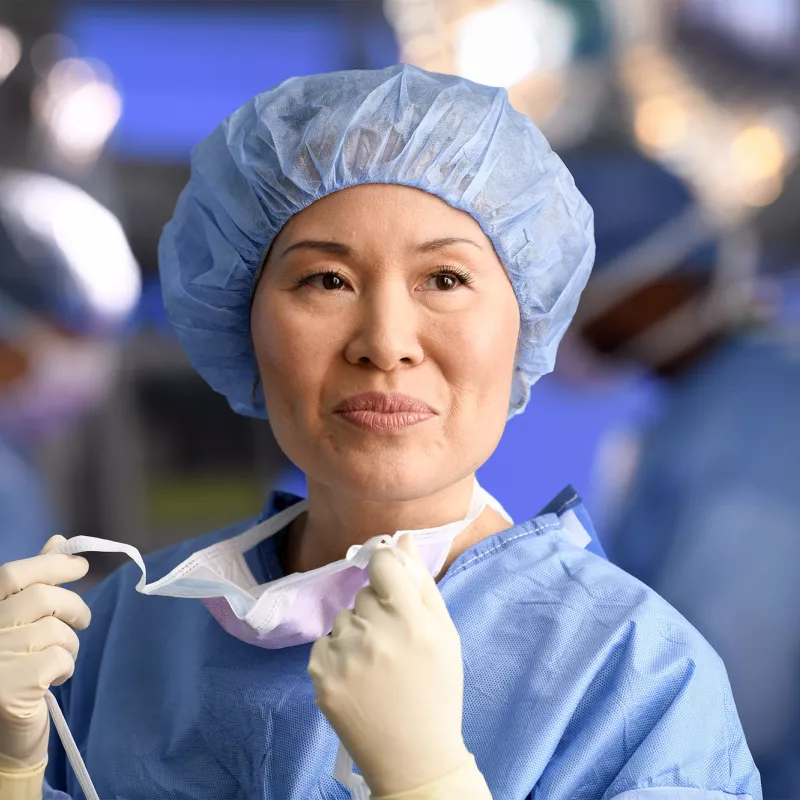 Smiling female surgeon taking off her mask