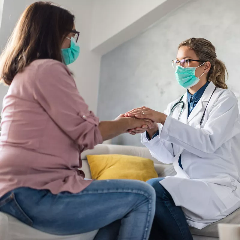 A female physician holding a female patient's hand