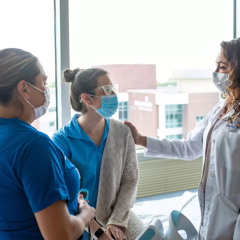 Physician and nurse talking with a patient.