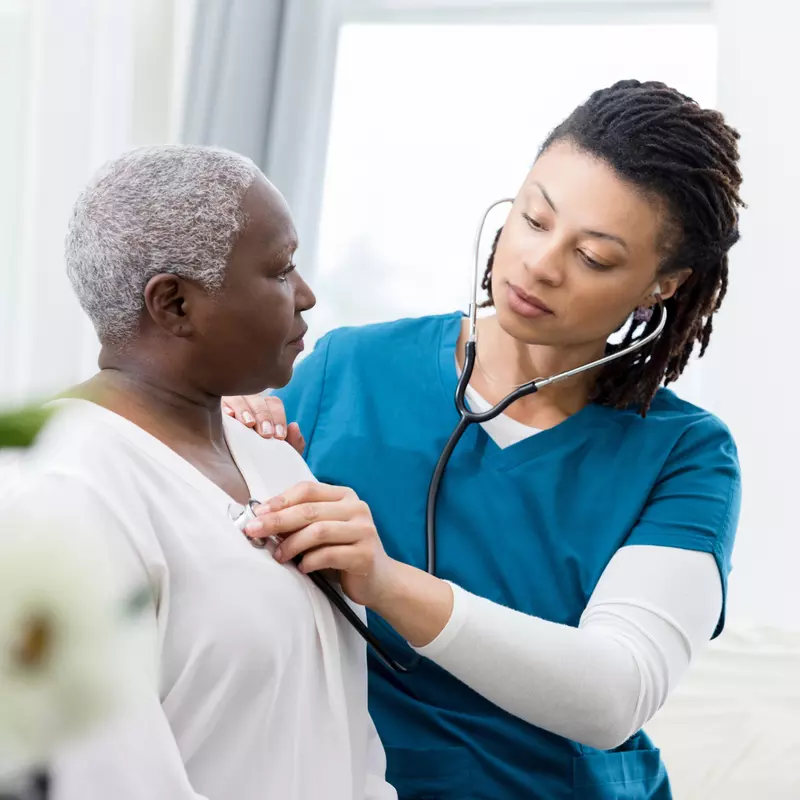 Nurse checking a woman patient's heartbeat.