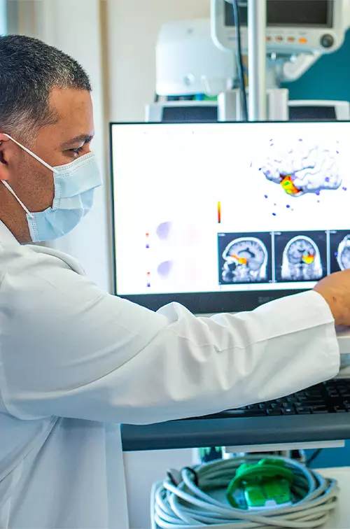 Physician pointing at a brain scan on a screen.